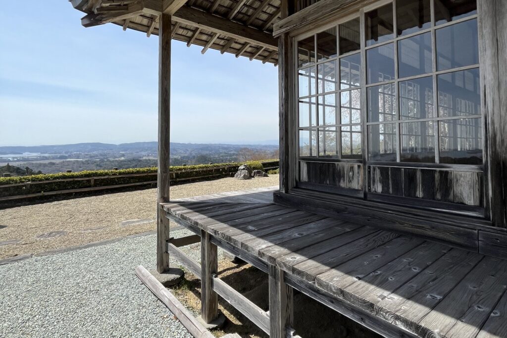 The weathered wooden veranda of Daigyoji Temple, empty of visitors, with Matsushima Bay in the distance